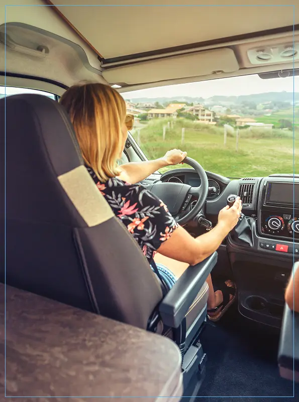 A camper van on the road with two people inside, capturing the essence of adventure and travel.